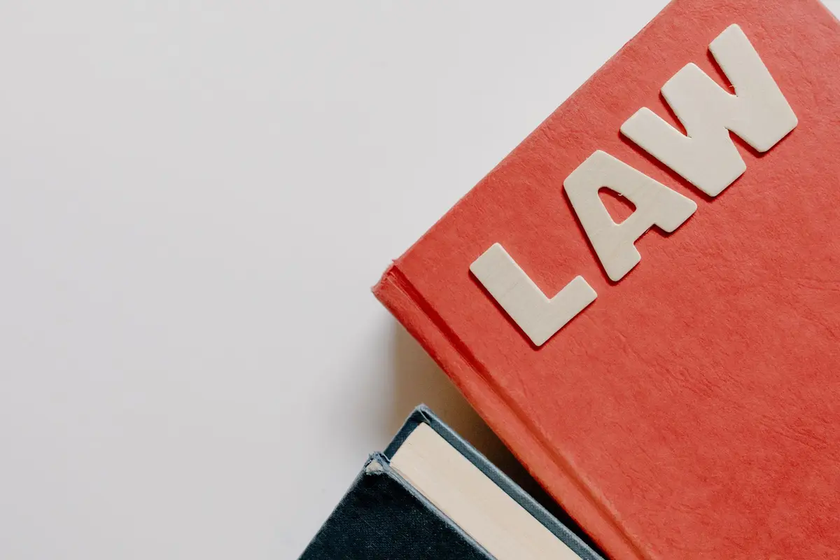 A red law textbook resting on a dark hardback book